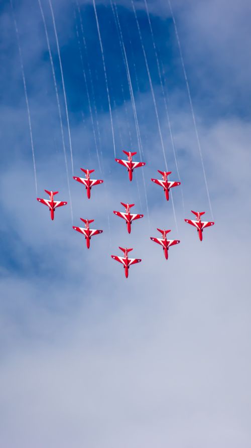 Free Nine red aircrafts in precision flight against a blue sky at an airshow. Stock Photo