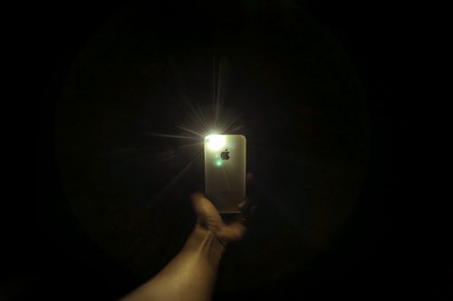 Person holding smartphone with light glowing in a dark room