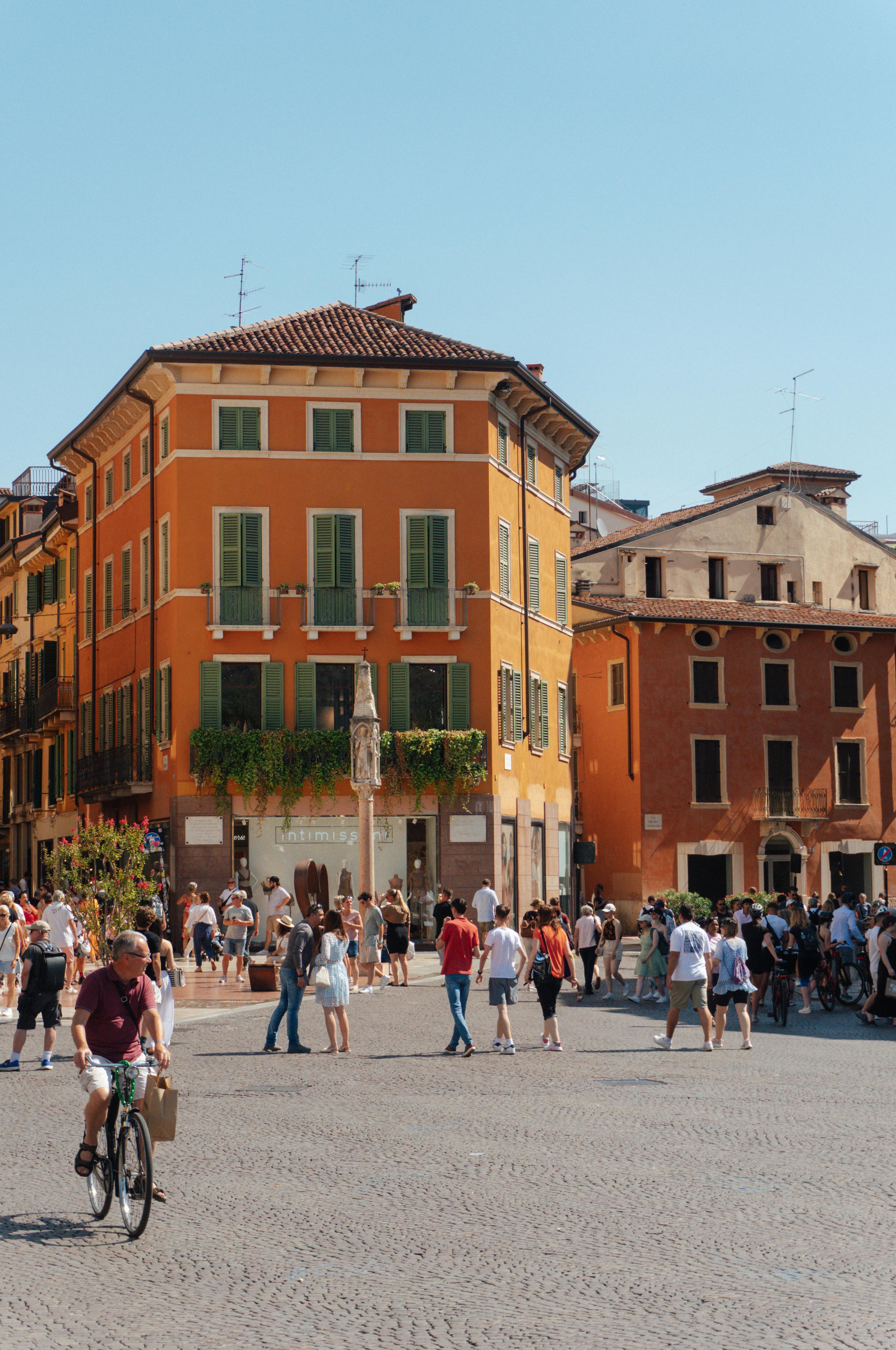A lively street in Verona's historic center, showcasing colorful buildings and bustling activity.