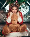穿着圣诞老人服装的年轻女子抱着一只泰迪熊，洋溢着节日的欢乐