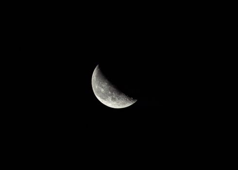 Captivating photo of a bright half moon against a dark night sky, showcasing lunar details.
