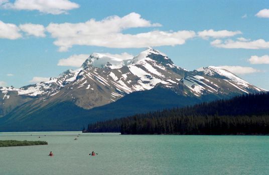 Majestic view of Maligne Lake with snow-capped mountains and canoes, Jasper National Park.