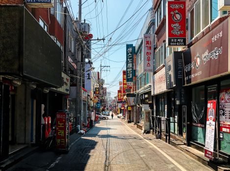 Explore a bustling street in Korea, lined with colorful signs and shops during the day.