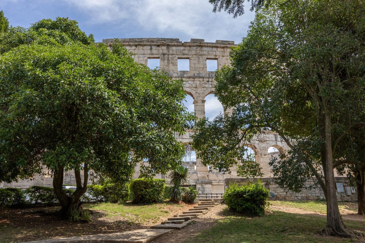Amfiteatrul roman din Pula văzut printre copaci, cu arcadele de piatră intacte
