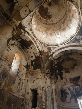 Aged church interior featuring worn frescoes under a domed ceiling.