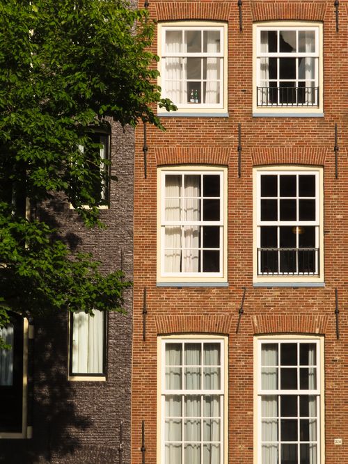 Free Sunlit brick facades with classic windows in Amsterdam's urban landscape. Stock Photo