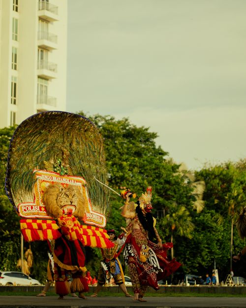 Free Captivating traditional Indonesian dance with vibrant costumes in a modern city backdrop. Stock Photo