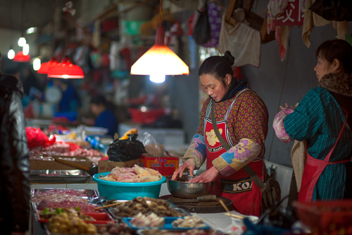 Free Busy market in Guilin, Guangxi, China with vendors preparing fresh foods under warm lights. Stock Photo