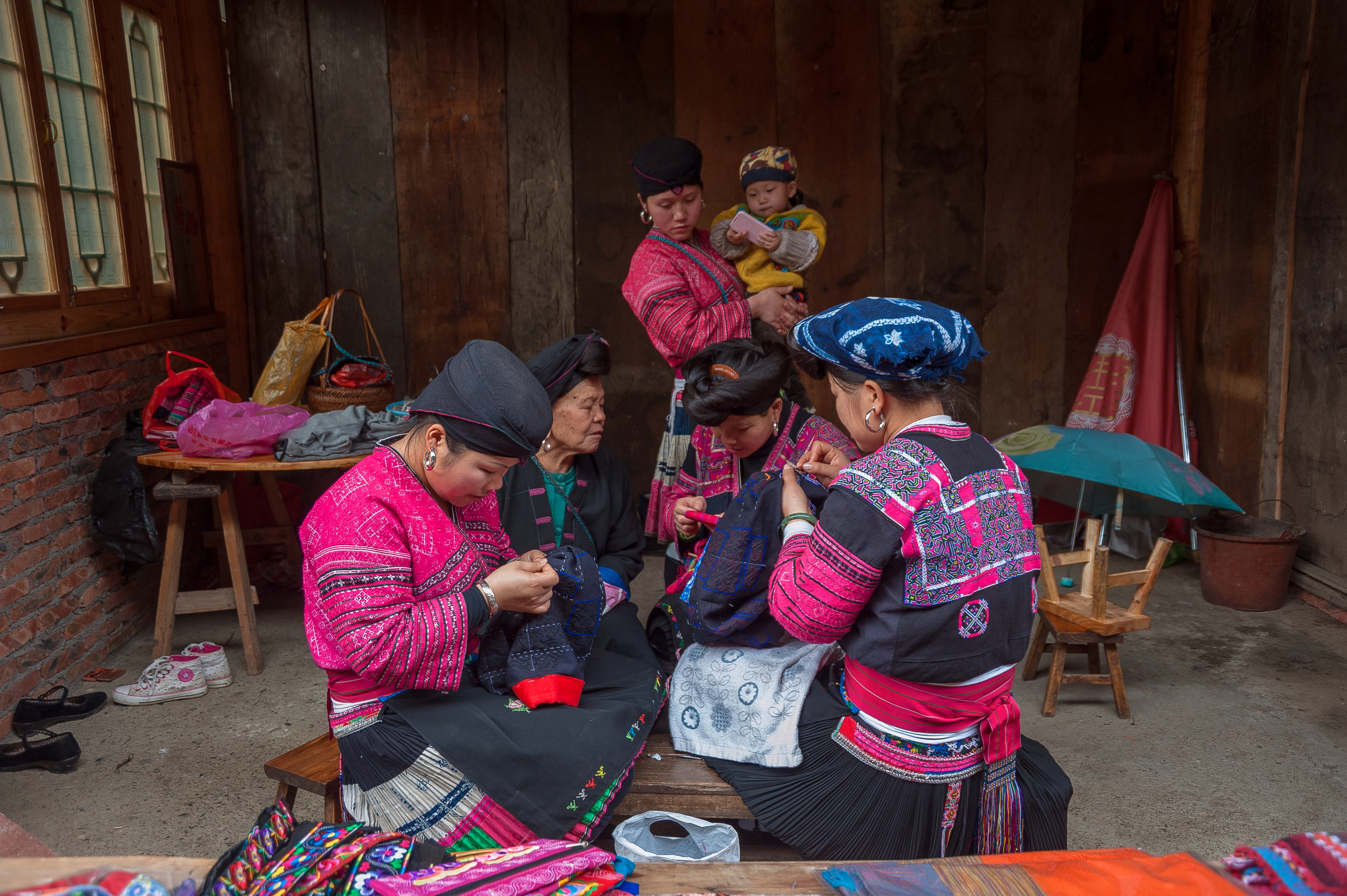 Women in traditional attire engaging in needlework in Guilin, China — the living craft tradition behind the Chinese embroidery shoulder bag