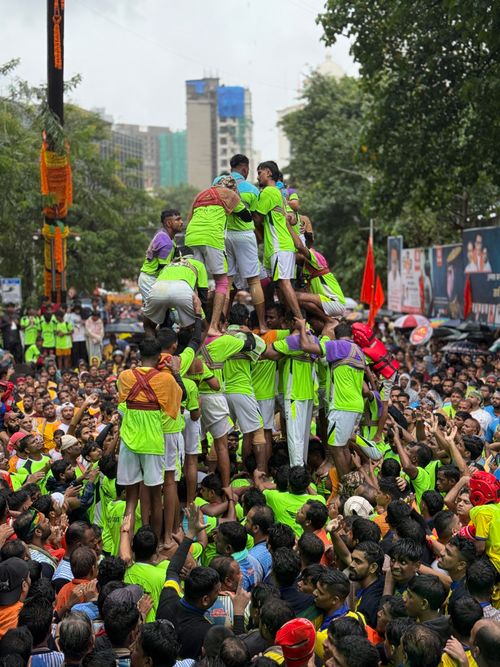 Free Vibrant Dahi Handi festival with a human pyramid in a lively outdoor setting. Stock Photo