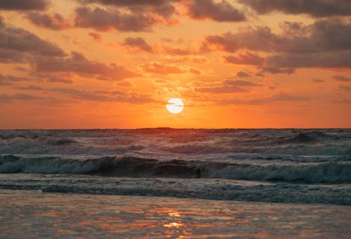 Free Scenic ocean sunset with waves crashing, creating a serene and dramatic seascape. Stock Photo