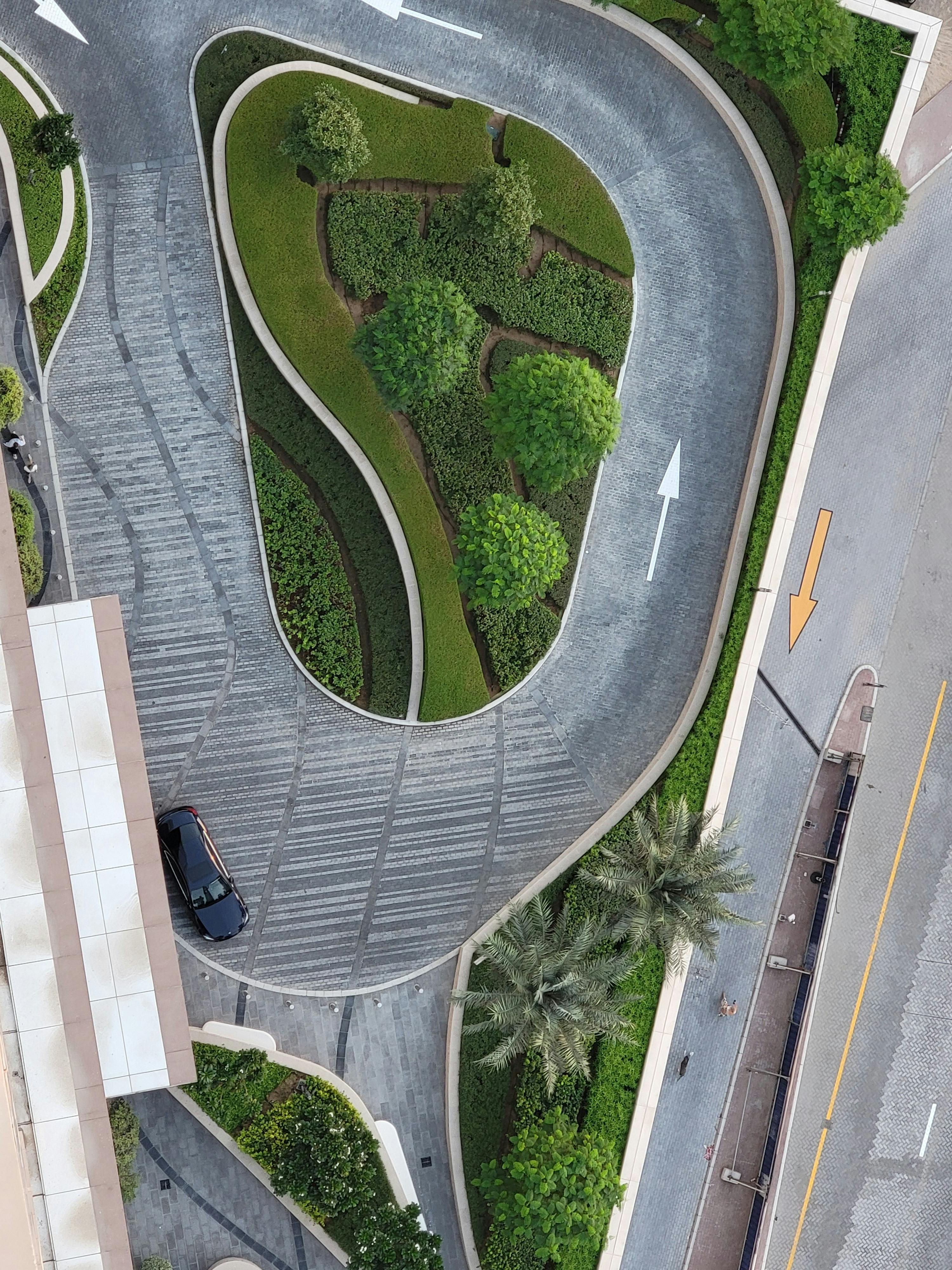 Aerial view of an urban circular road surrounded by lush greenery and directional arrows.