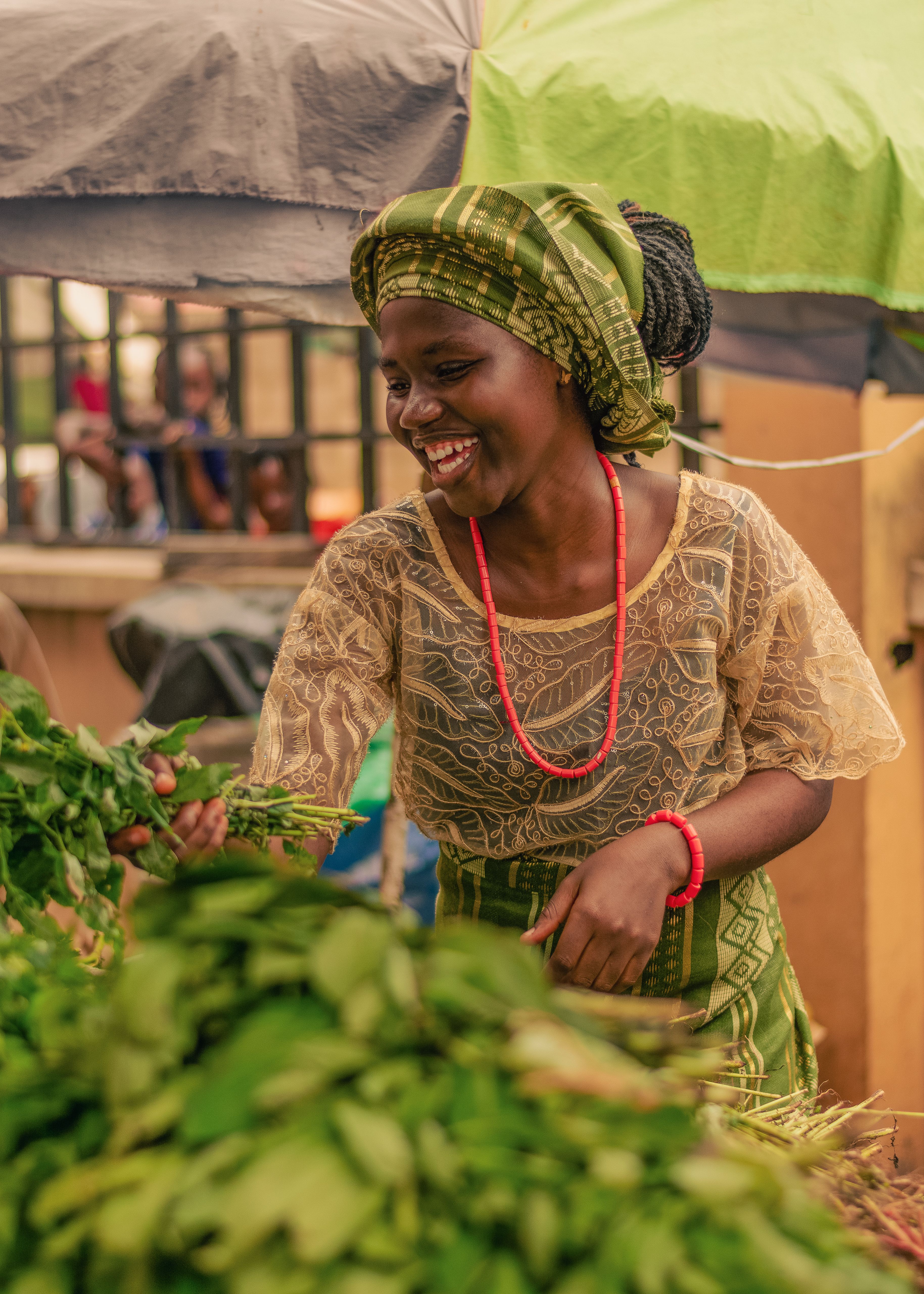 A woman tending vegetables at her market stall in the morning light
