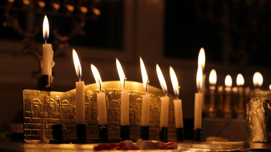 Warm glow of lit menorah candles celebrating Hanukkah indoors during evening hours.