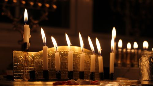 Free Warm glow of lit menorah candles celebrating Hanukkah indoors during evening hours. Stock Photo