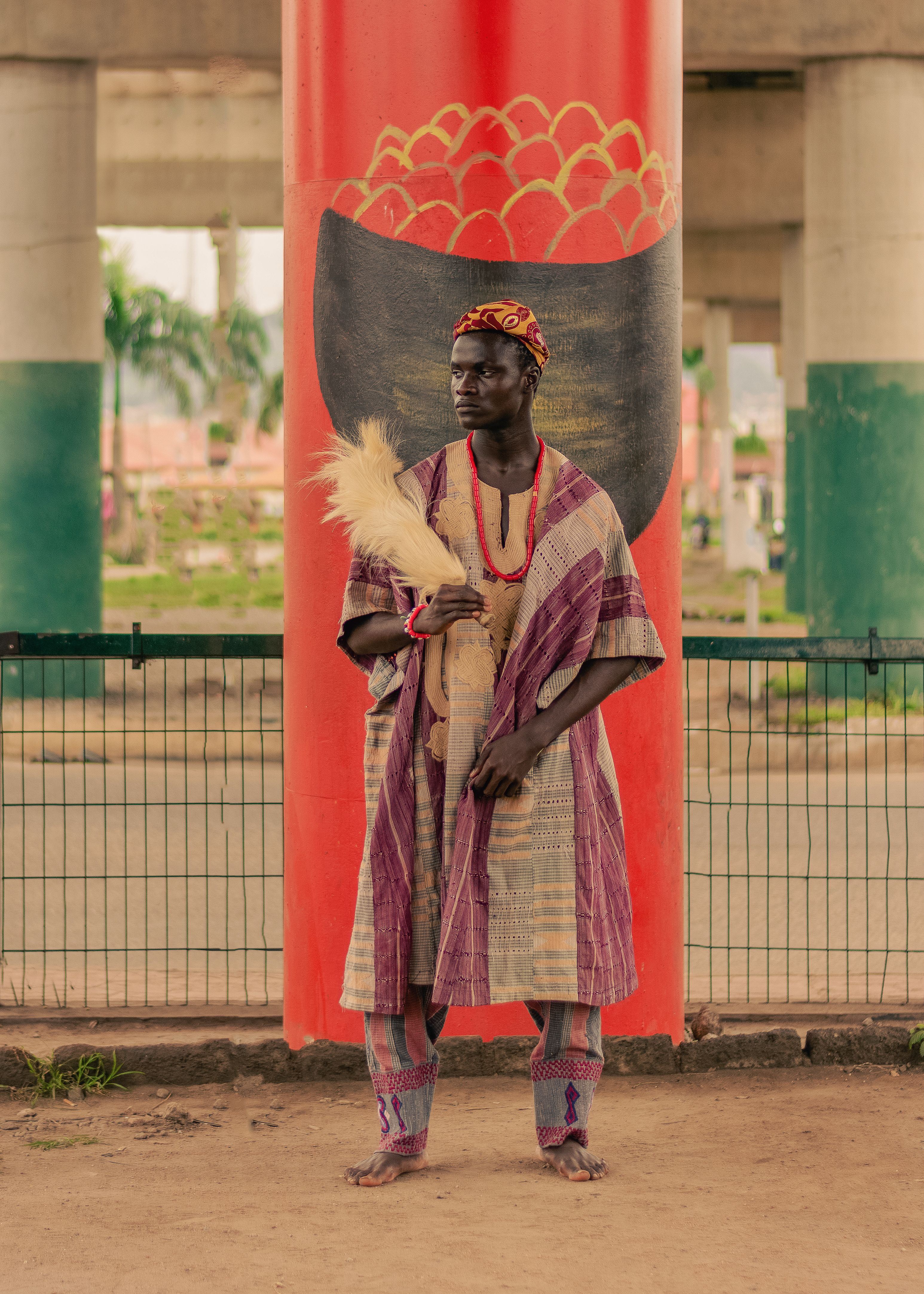 Portrait of a man in traditional African clothing standing under a vibrant overpass.