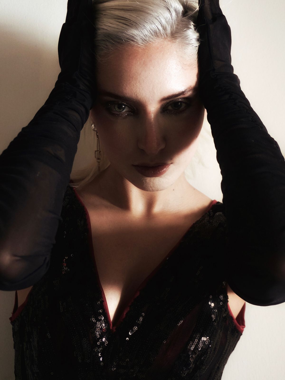 An elegant woman in dramatic lighting with black gloves — the statement black dress