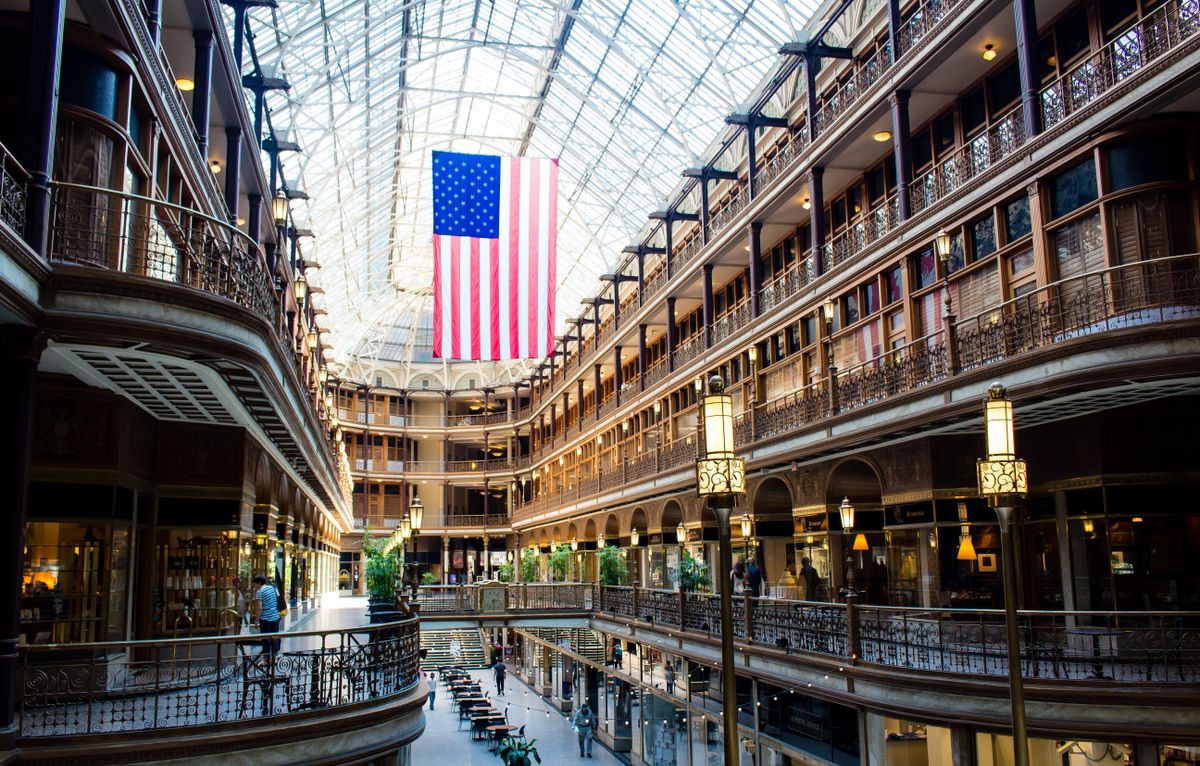 Historic grand arcade and shopping corridor beneath an American flag