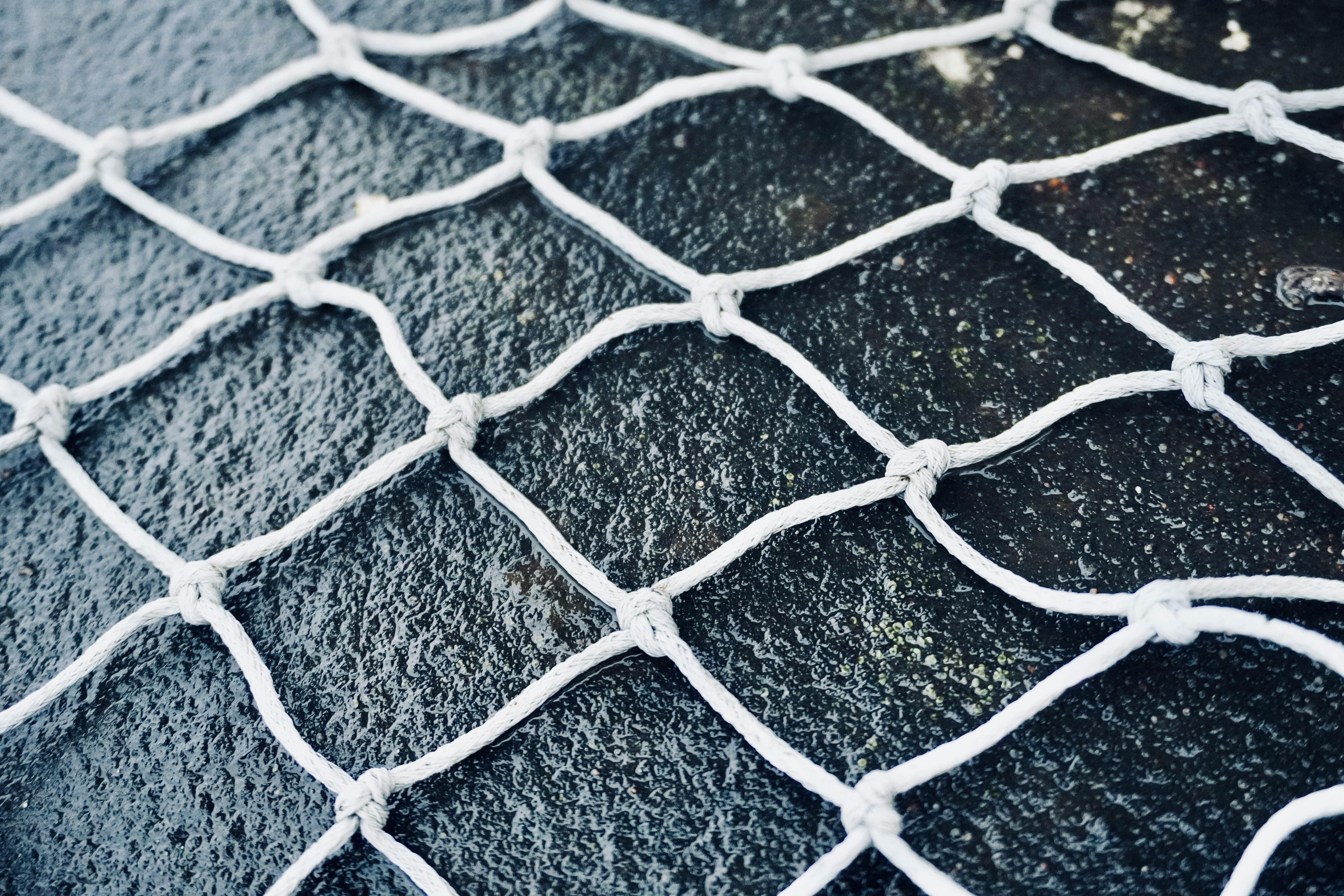 Free High-resolution close-up of white netting against a dark textured background, highlighting grid pattern. Stock Photo
