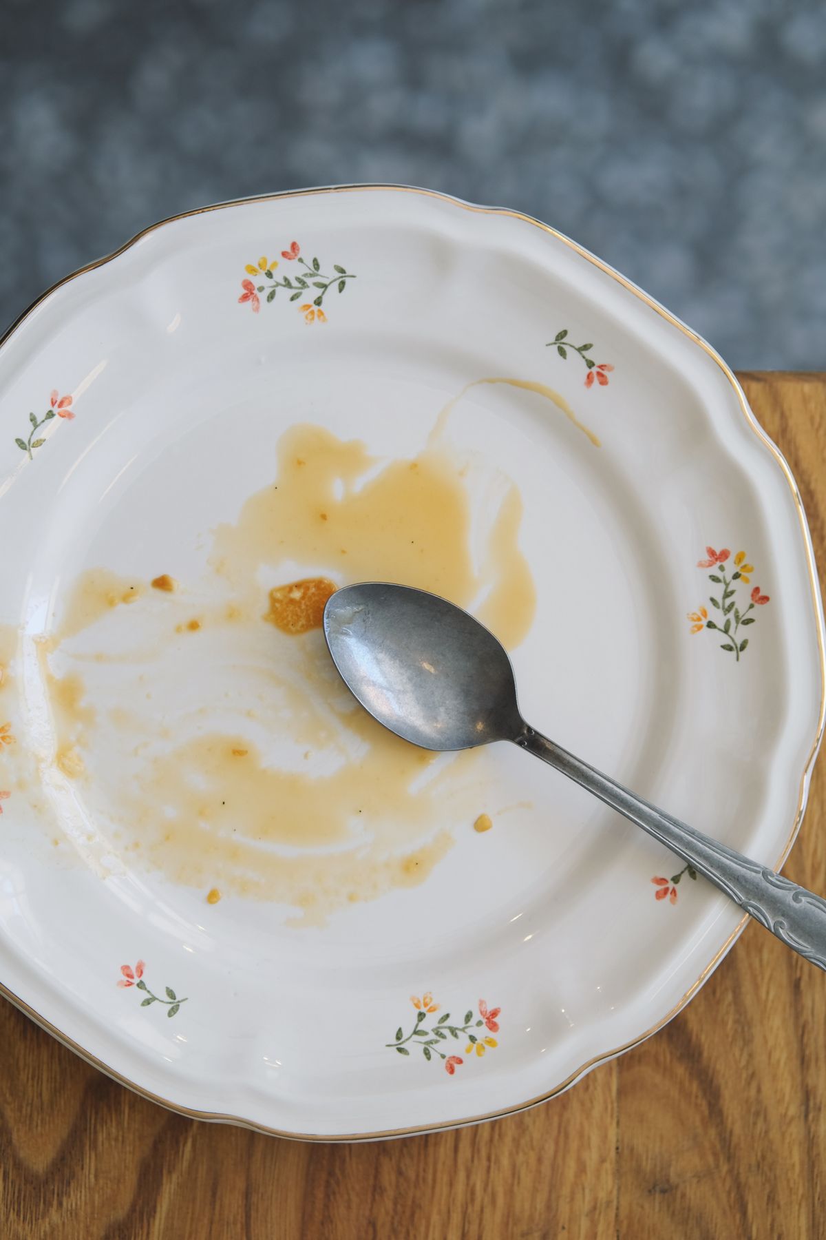 Plato vacío con una cuchara y restos de comida sobre una mesa de madera, símbolo del final de la ventana de alimentación en el ayuno intermitente