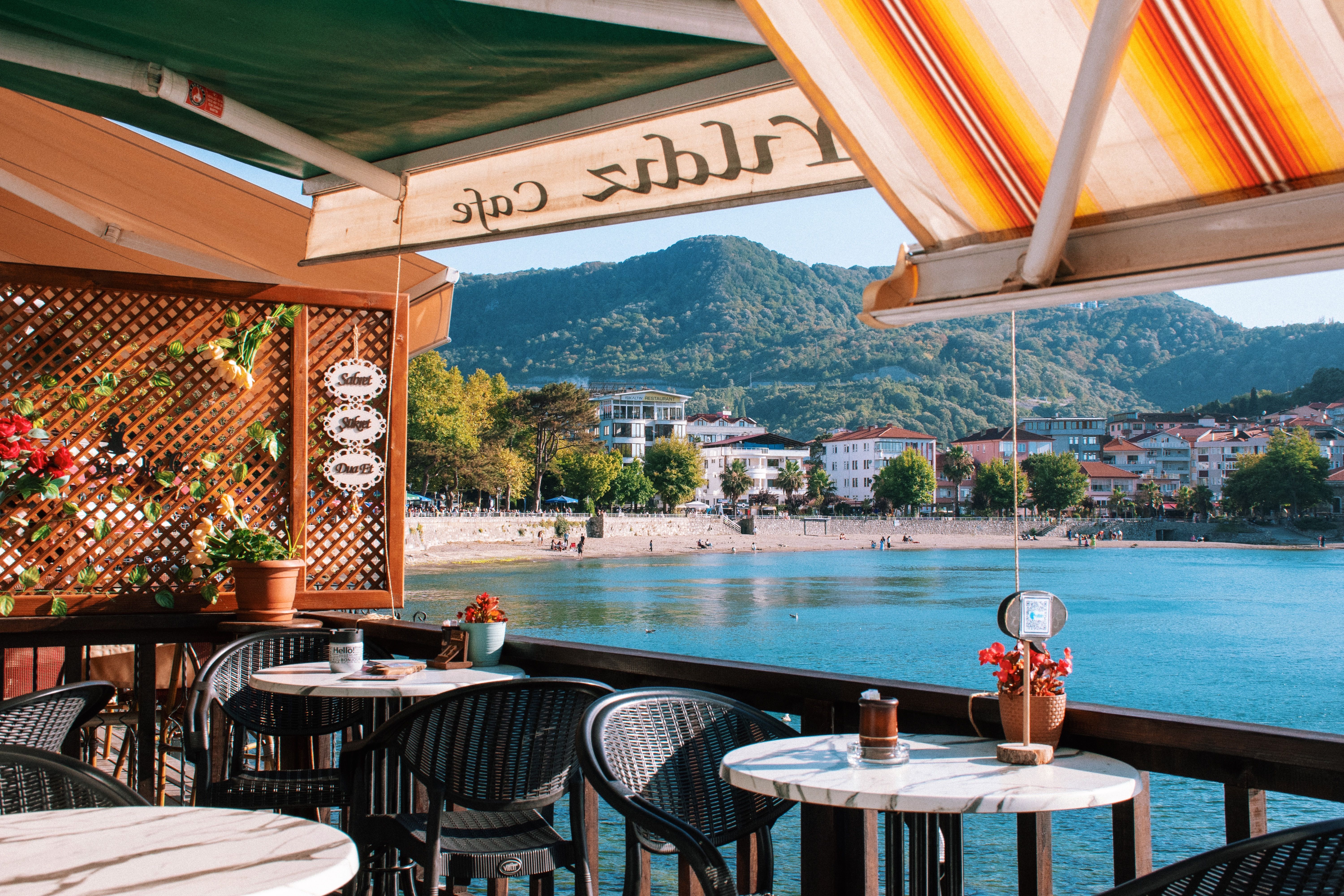 Cozy cafe overlooking a serene lake with scenic mountain backdrop.