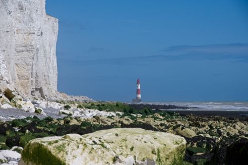 Free Panoramic view of Beachy Head's iconic lighthouse and towering chalk cliffs on a sunny day. Stock Photo