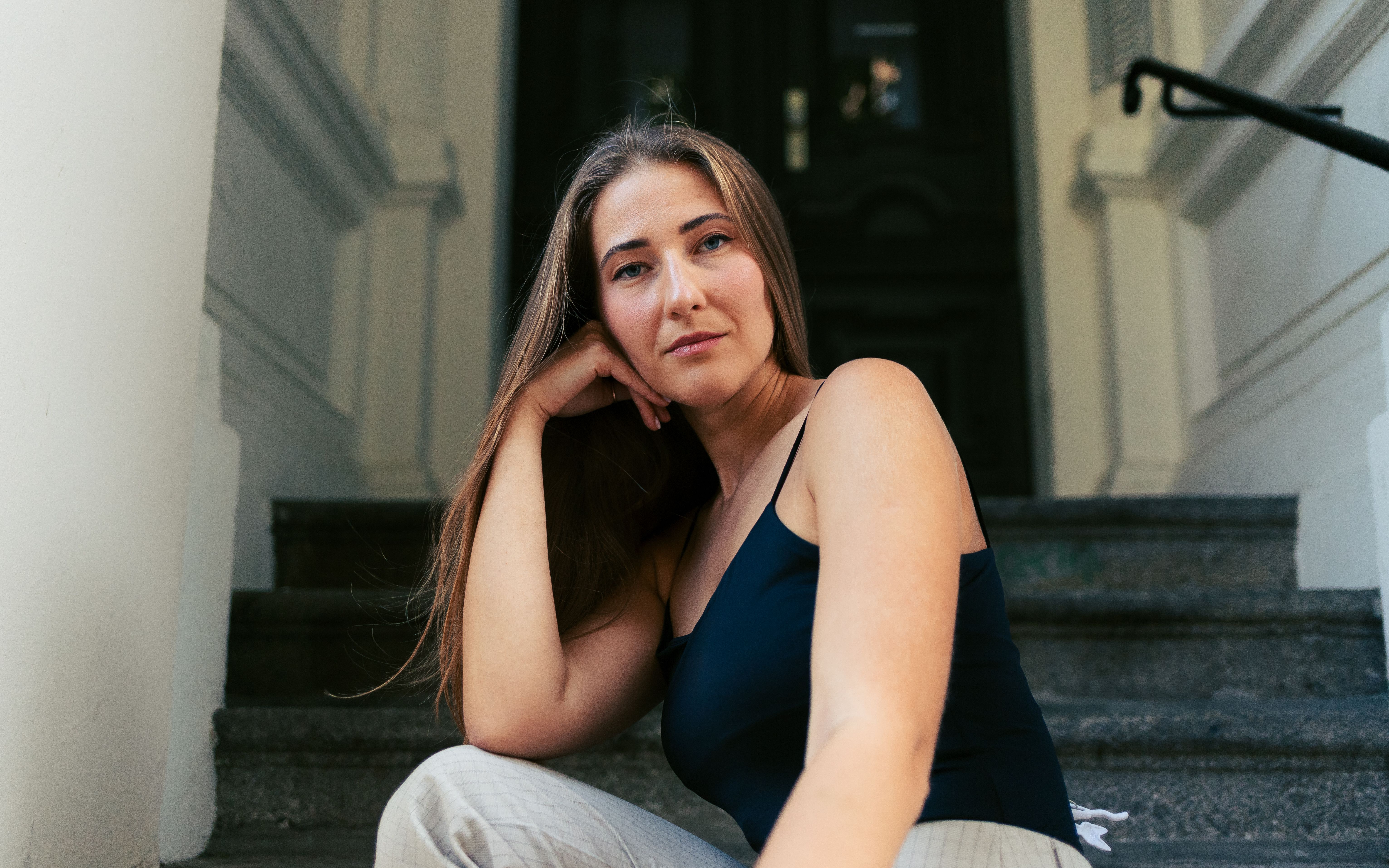 Portrait of a woman sitting on steps in Berlin, capturing a relaxed moment.