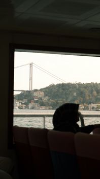 Silhouette of a person on ferry viewing the Bosphorus Bridge, Istanbul.
