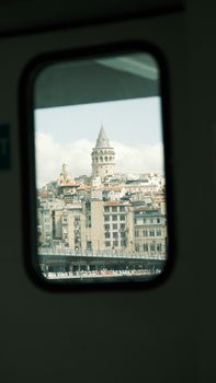 Unique perspective of Istanbul's Galata Tower seen through a ferry window.