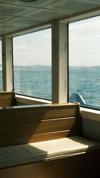 Peaceful boat interior with ocean view through large windows on a sunny day.