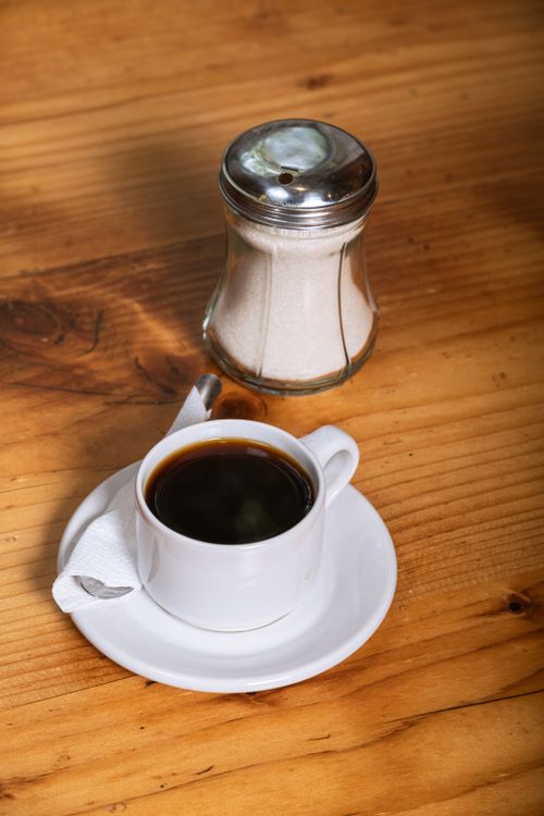 Free A warm cup of black coffee with sugar jar on a rustic wooden table, evoking a cozy morning vibe. Stock Photo