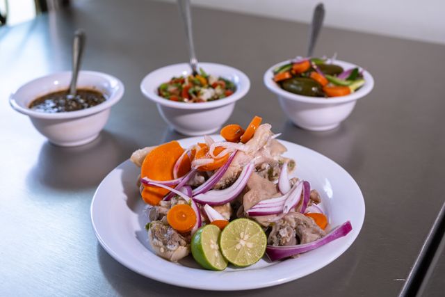 Plate of Mexican food with onions and carrots, accompanied by sauces and colorful sides.