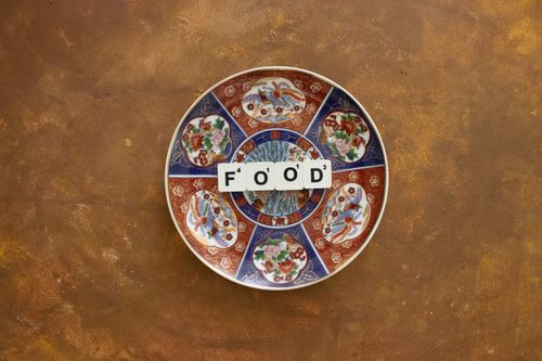 Free An overhead view of a decorative plate with Scrabble letters spelling 'Food' on a rustic surface. Stock Photo