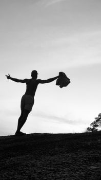 Silhouette of a person standing with arms outstretched at sunset, creating a dramatic scene.