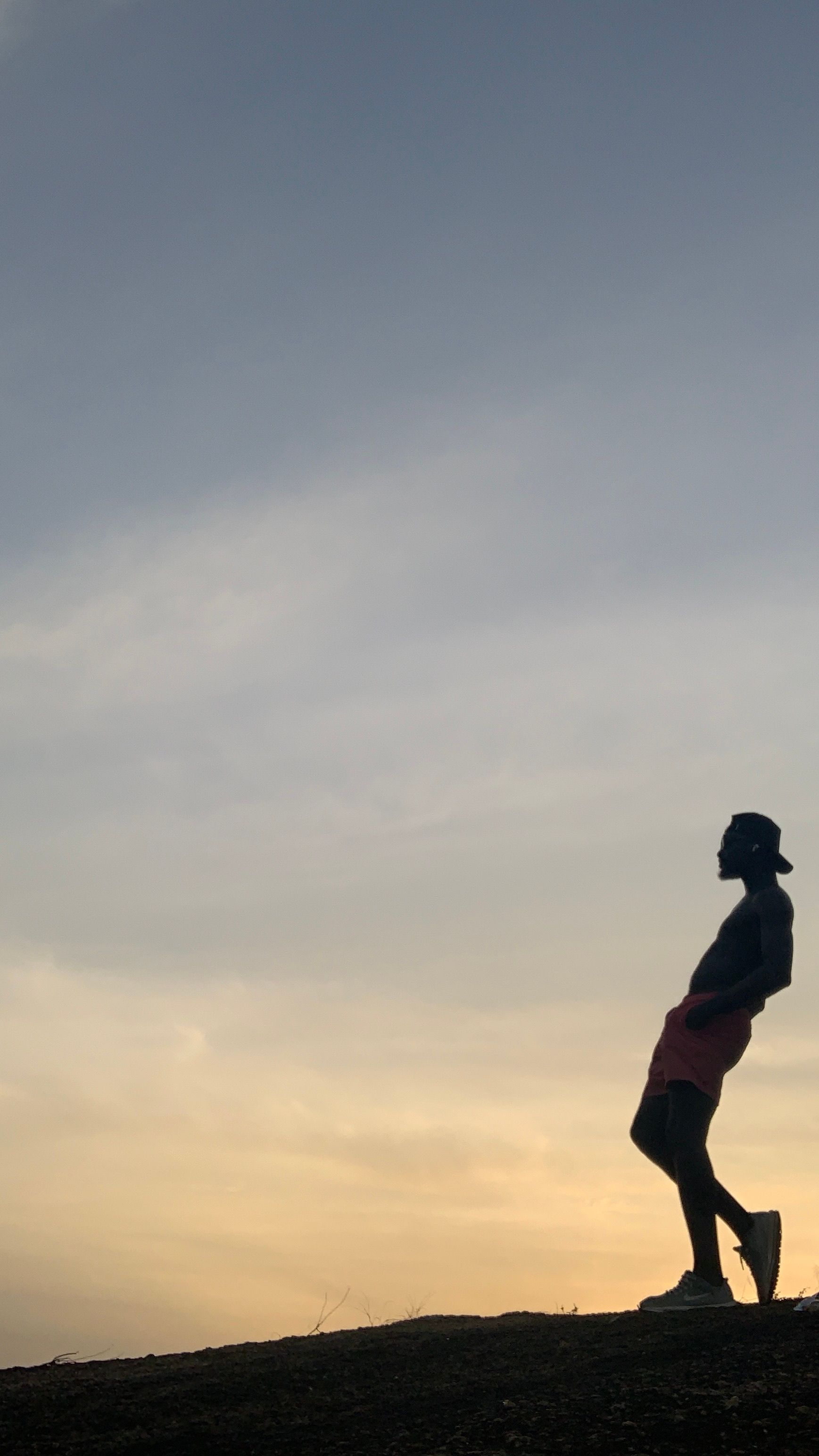 A silhouette of a man leaning back with a sunset backdrop, creating a serene and reflective scene.