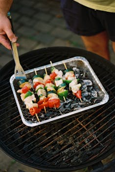 Juicy vegetable and chicken skewers grilling outdoors on a charcoal barbecue.