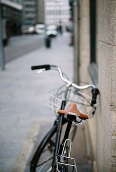 Close-up of a vintage bicycle with brown leather seat parked on a stone street in an urban setting.