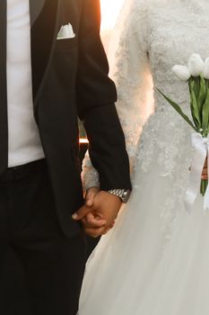 Beautiful capture of a couple holding hands during a sunset wedding ceremony.
