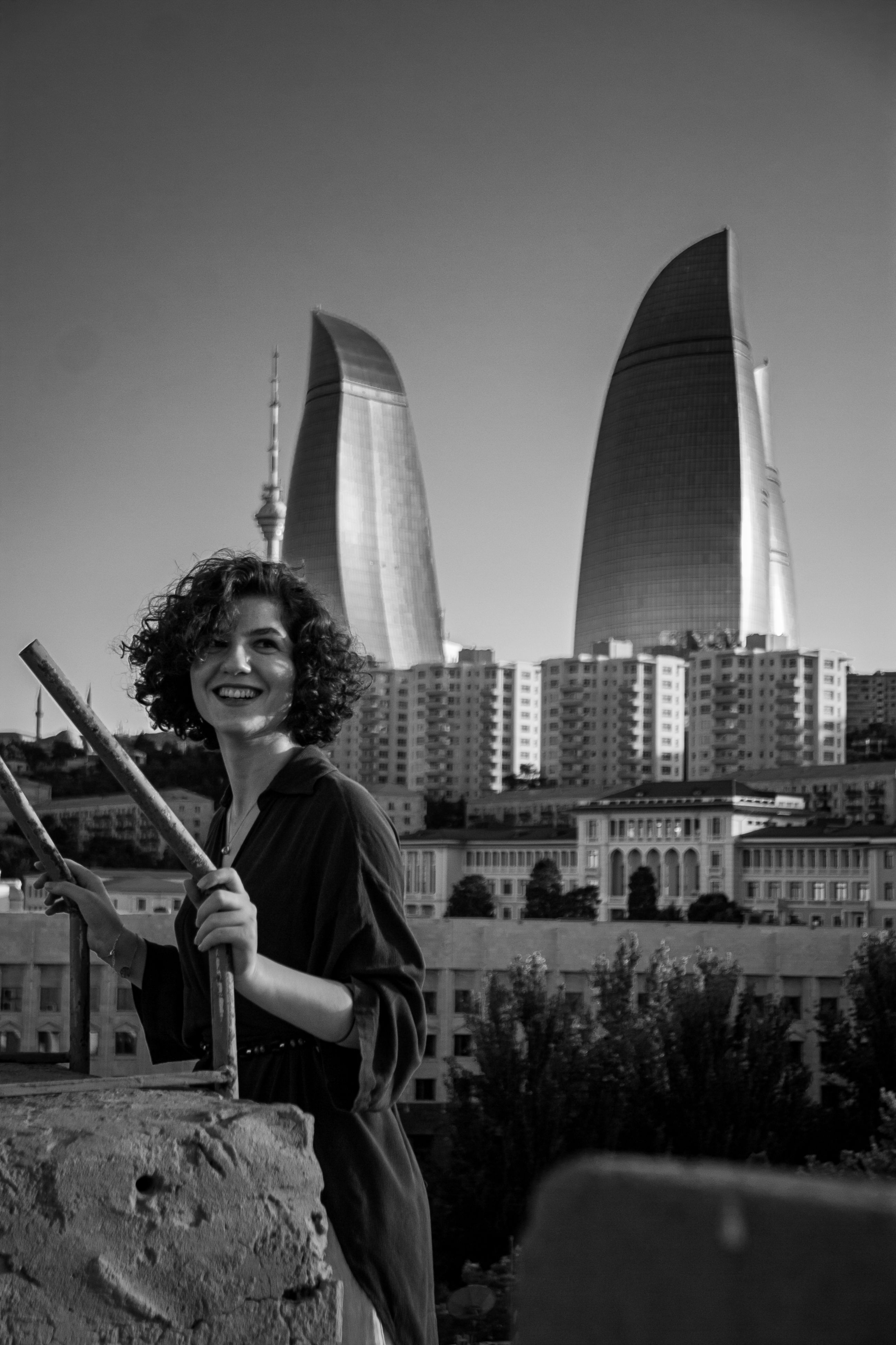 A woman smiles with the iconic Flame Towers of Baku in the background, captured in elegant black and white.