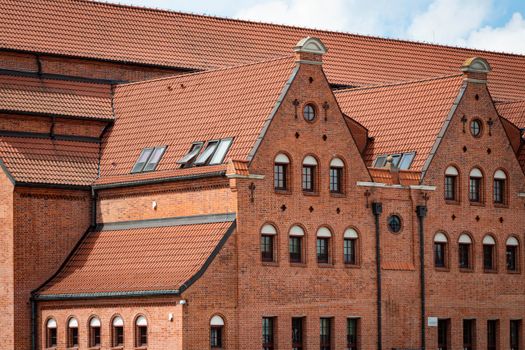 Red brick facade of a historic building in Gdańsk, Poland with intricate roof design.