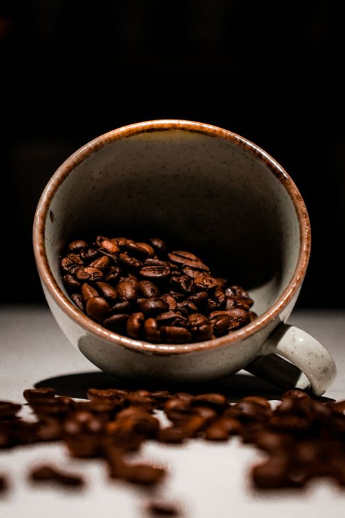 Free Aesthetic close-up of coffee beans spilling from a ceramic cup, highlighting rich textures. Stock Photo