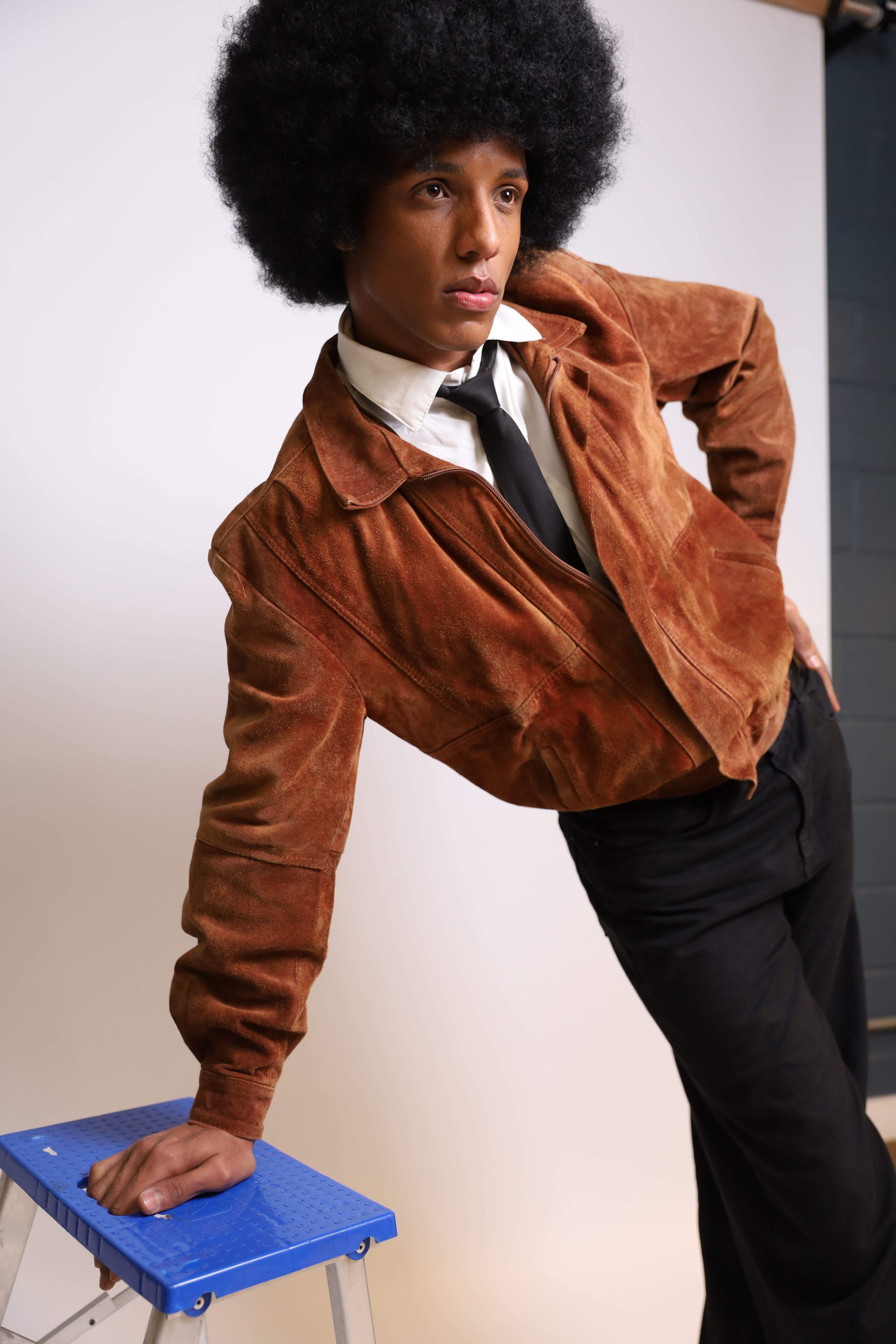 Portrait of a stylish individual in vintage attire with afro hairstyle.