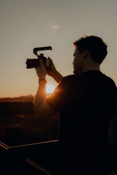Silhouette of a person capturing photos with a camera during a serene sunset outdoors. - Fotografer Sidoarjo