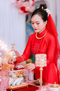 Bride in traditional red dress preparing a ceremonial offering in an elegant wedding setting.