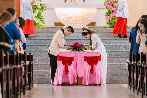 Free Bride and groom exchange respectful bows in a beautifully decorated church setting. Stock Photo