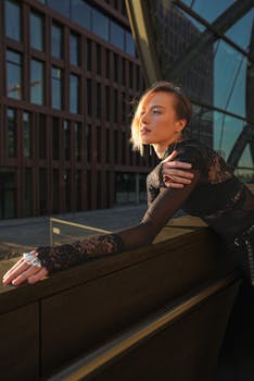 Stylish woman in black lace outfit poses outdoors in Hamburg's cityscape.