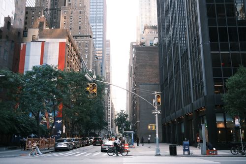 Free Busy city street with pedestrians and cyclists surrounded by towering buildings and traffic lights. Stock Photo