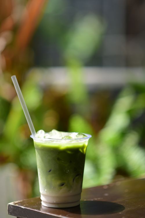 Free Iced matcha latte with a straw on a table outdoors, perfect for a refreshing break. Stock Photo