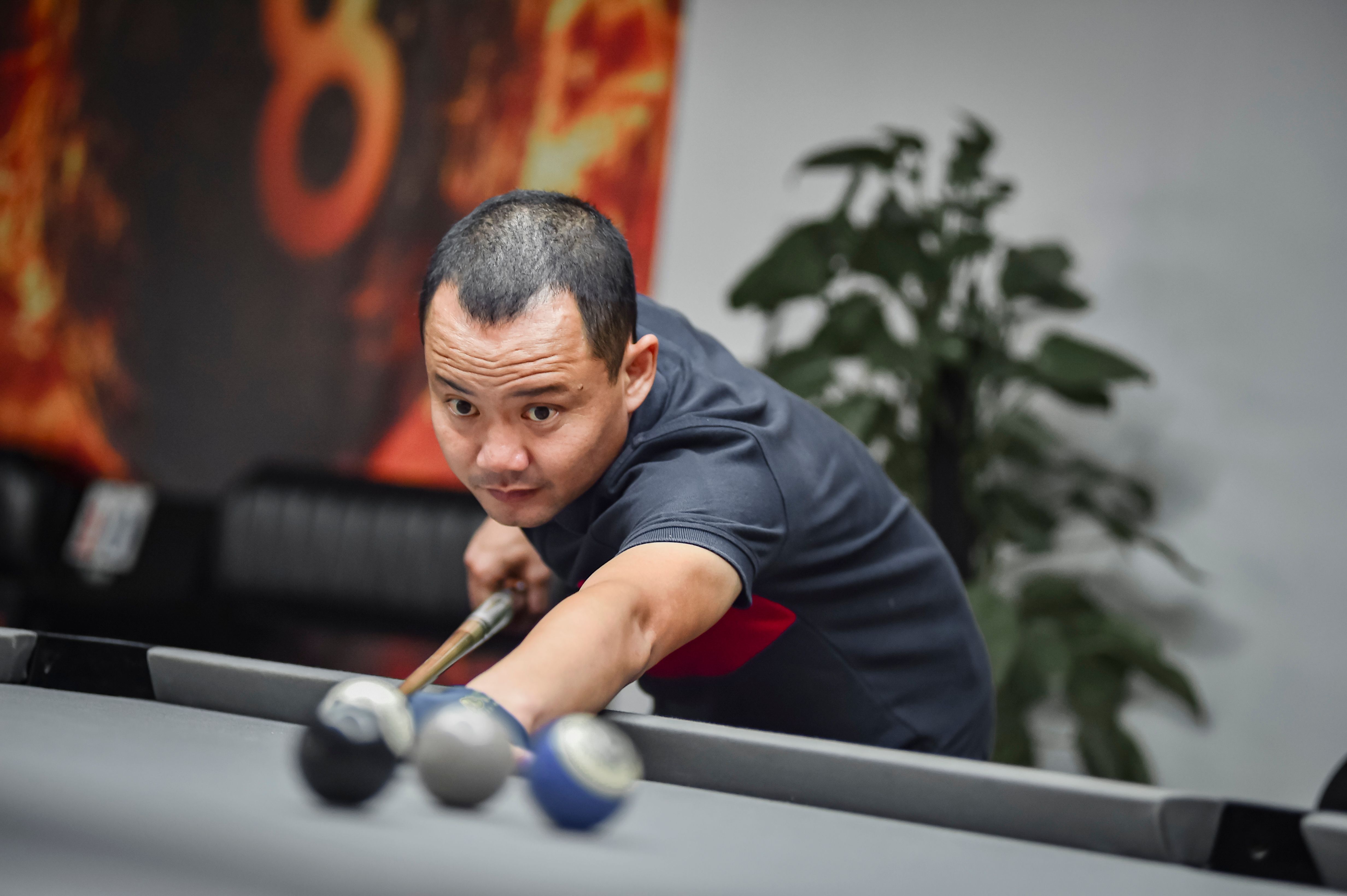 Focused snooker player aiming for a shot in an indoor game room in Hà Nội, Việt Nam.