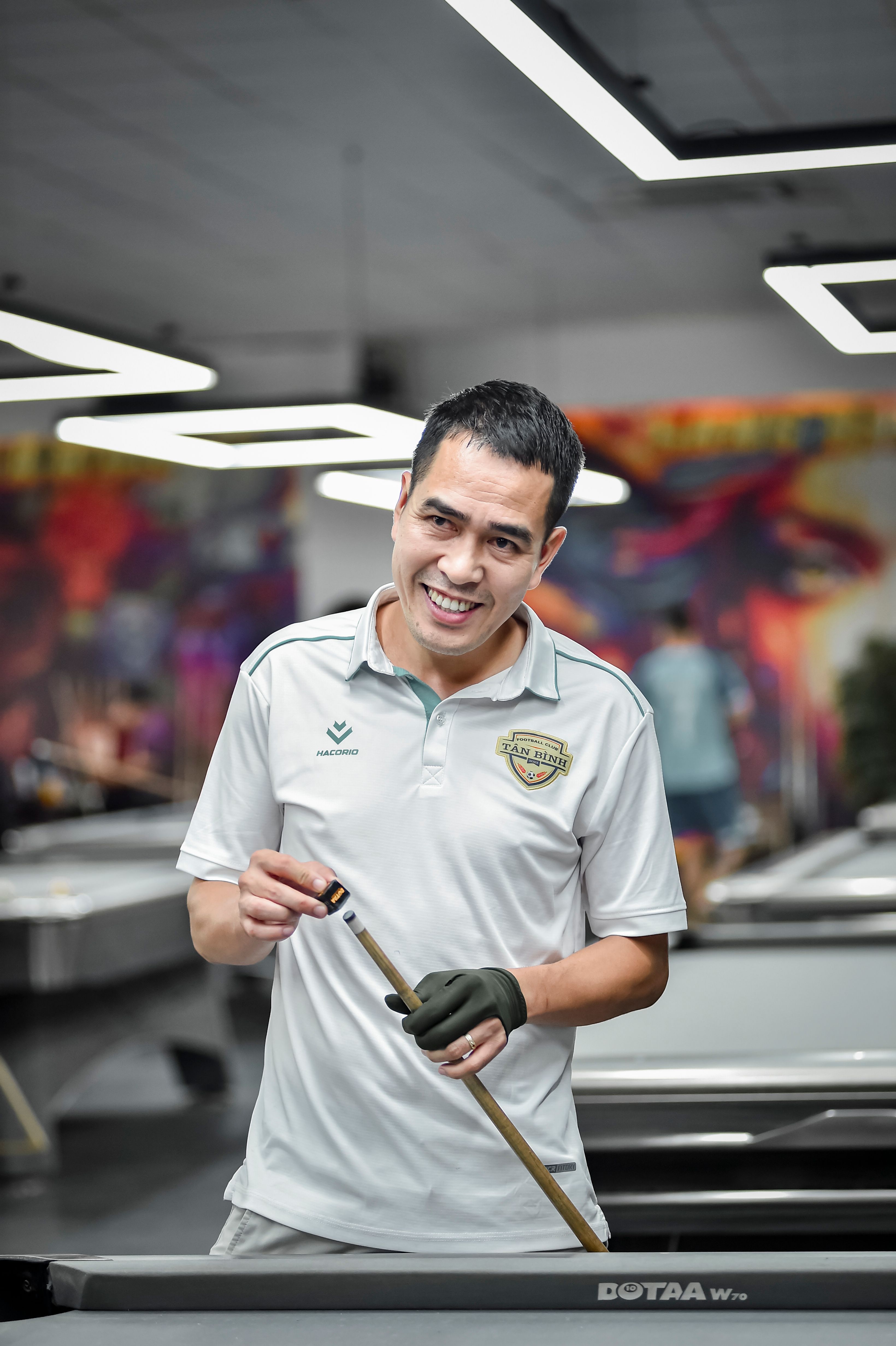 A smiling man plays pool indoors at a billiards center in Hà Nội, Vietnam.